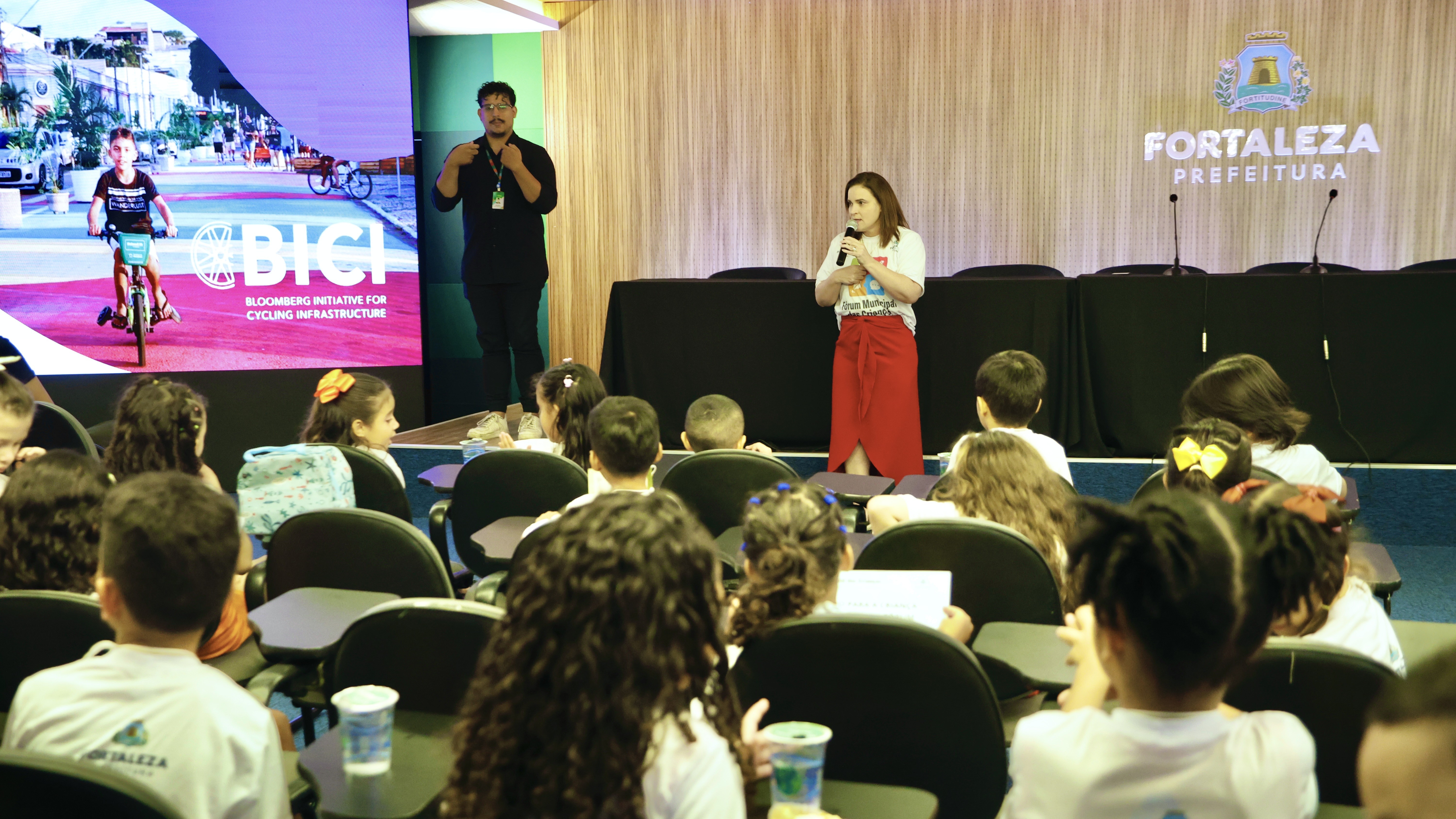 primeira dama fala ao microfone diante da plateia de crianças no auditório do Paço